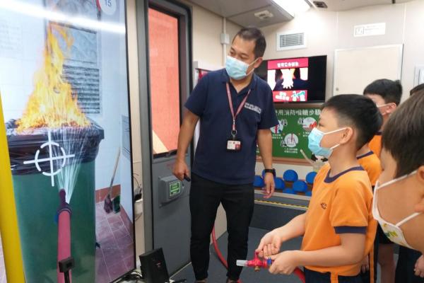 消防員正指導同學如何使用滅火筒。